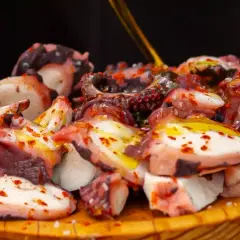 Pezzi di polpo succulento, conditi con olio e paprika, pronti per la cottura. Un piatto che celebra la bontà del mare.