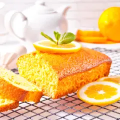 Un delizioso plumcake al limone, decorato con fette d'arancia e menta, pronto per essere gustato.