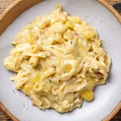 Un piatto invitante di pasta con patate cremosa, arricchita da pezzetti di pancetta e prezzemolo fresco.