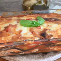 Parmigiana di melanzane appena sfornata, dorata e filante, guarnita con basilico fresco. Un classico della cucina italiana.