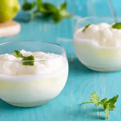 Due bicchieri di sorbetto al limone veloce, guarniti con menta fresca, su un tavolo di legno blu.