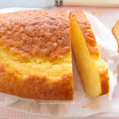 Un soffice plumcake allo yogurt, dorato e invitante, con una fetta tagliata che ne mostra la morbidezza. Perfetto per la colazione.