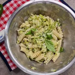 Pasta fredda con zucchine, basilico e formaggio fresco. Un piatto estivo leggero e gustoso, pronto per essere servito.