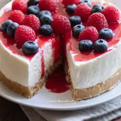 Cheesecake con mascarpone, guarnita con lamponi e mirtilli freschi, con una colata di salsa rossa.
