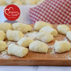 Gnocchi di ricotta freschi, pronti per essere cucinati, su un tagliere di legno.