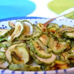 Fette di zucchine in carpione, condite con olio e aceto, pronte per essere gustate.