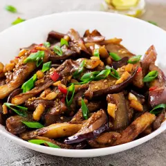 Melanzane in agrodolce, un piatto saporito con peperoncino, aglio e cipollotto, pronto per essere gustato con le bacchette.