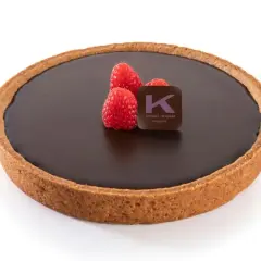 Una deliziosa crostata al cioccolato, con tre lamponi freschi e il logo di Ernst Knam.