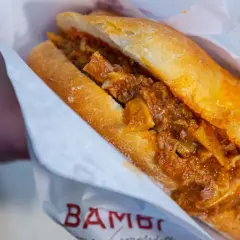 Panino con trippa alla fiorentina, un classico street food toscano, avvolto in carta con logo.