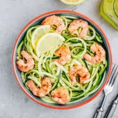 Spaghetti di zucchine con gamberi succulenti e spicchi di limone, un piatto leggero e gustoso.