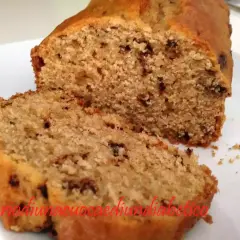 Plumcake con gocce di cioccolato, soffice e invitante, tagliato a fette su un piatto bianco.