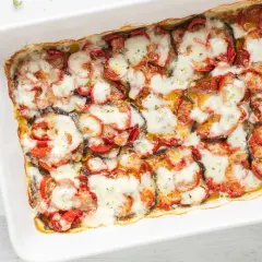 Melanzane al forno, un piatto invitante con fette di melanzane, pomodori e mozzarella filante, pronto per essere gustato.