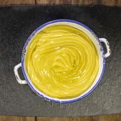 Una ciotola di cremosa crema pasticcera vegana, con un vortice lucido al centro, pronta per essere gustata.