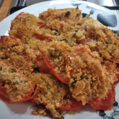 Pomodori al forno ripieni di pangrattato e erbe aromatiche, dorati e invitanti.