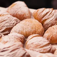 Un gruppo di sfogliatella riccia, dolci napoletani con pasta sfoglia croccante e ripieno cremoso, cosparsi di zucchero a velo.
