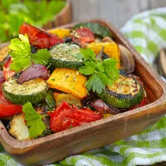 Un misto colorato di verdure in friggitrice ad aria, tra cui zucchine, peperoni e pomodori, guarnito con prezzemolo fresco.