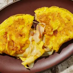 Omelette dorata e soffice, ripiena di formaggio filante. Una deliziosa omelette ricetta per una colazione o un pasto veloce.