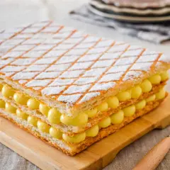 Una deliziosa torta millefoglie con strati di pasta sfoglia e crema pasticcera, cosparsa di zucchero a velo.