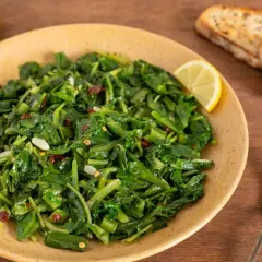 Piatto di cicoria ripassata con aglio, peperoncino e limone, accompagnato da crostini tostati.