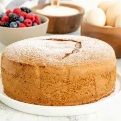 Una soffice torta margherita spolverata di zucchero a velo, pronta per essere gustata con frutti di bosco freschi.
