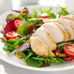 Tagliata di pollo succulenta su un letto di insalata fresca con pomodorini, cipolla rossa e senape.