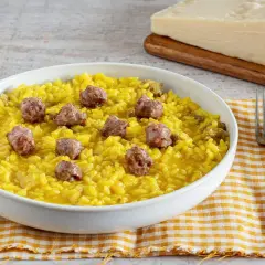 Un invitante risotto alla monzese, giallo intenso e arricchito da pezzetti di salsiccia, pronto per essere gustato.