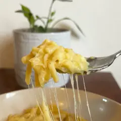 Un primo piatto cremoso: pasta e patate con provola filante, servita su una forchetta.
