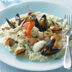 Un cremoso risotto alla pescatora, ricco di gamberi, cozze e calamari, pronto per essere gustato.