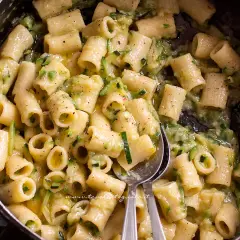 Close-up of rigatoni pasta with zucchini in a creamy sauce in a pot.