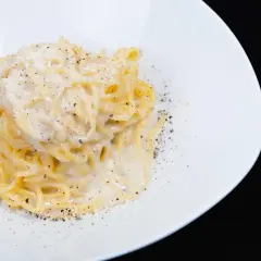 Spaghetti cremosi con formaggio e pepe nero, un classico della cacio e pepe ricetta, serviti su un piatto bianco.