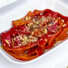 Peperoni al microonde, dolci e succosi, conditi con aglio tritato e spezie, serviti in una ciotola bianca.