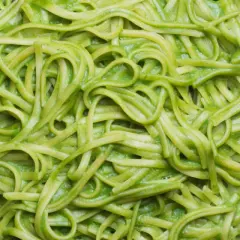 Pasta fresca condita con una cremosa salsa verde, probabilmente crema di zucchine per pasta, servita in un piatto scuro.