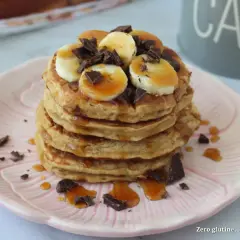 Pancake light con banana, cioccolato e sciroppo d'acero su un piatto rosa.