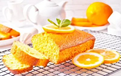 Un delizioso plumcake al limone, decorato con fette d'arancia e menta, pronto per essere gustato.