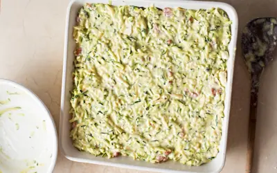 Sformato di zucchine pronto per essere infornato, con zucchine grattugiate e un cremoso impasto.