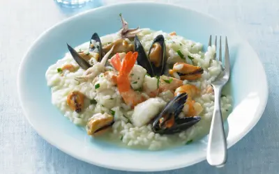 Un cremoso risotto alla pescatora, ricco di gamberi, cozze e calamari, pronto per essere gustato.