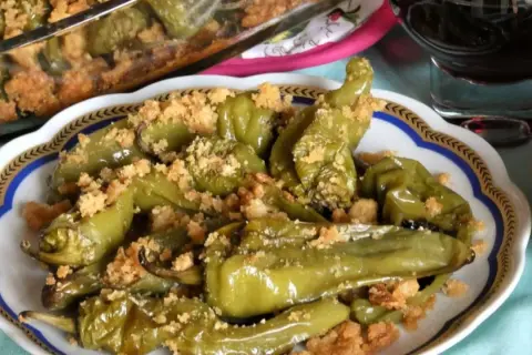 Friggitelli al forno, verdi e succosi, cosparsi di pangrattato croccante. Un contorno saporito e invitante.