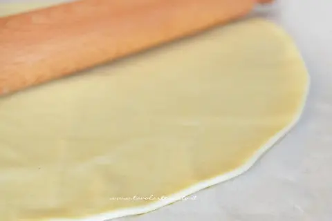 Mattarello stende la pasta brise su carta forno, pronta per una torta salata.