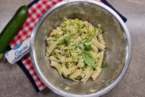 Pasta fredda con zucchine, basilico e formaggio fresco. Un piatto estivo leggero e gustoso, pronto per essere servito.