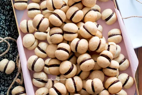 Una teglia piena di deliziosi baci di dama, biscotti friabili con un cuore di cioccolato fondente.
