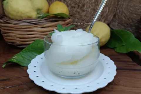 Una coppa di granita al limone, fresca e dissetante, con limoni freschi sullo sfondo.