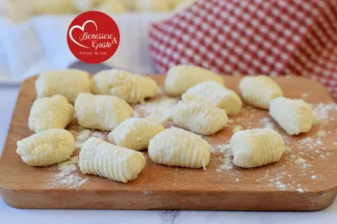 Gnocchi di ricotta freschi, pronti per essere cucinati, su un tagliere di legno.