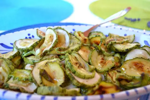 Fette di zucchine in carpione, condite con olio e aceto, pronte per essere gustate.