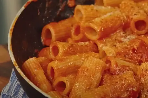 Rigatoni conditi con un sugo rosso ricco e cremoso, pronti per essere gustati in una **pasta alla zozzona** da leccarsi i baffi.