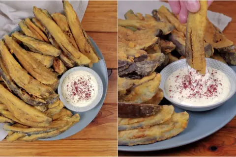 Piatto di melanzane fritte dorate e croccanti, servite con una ciotolina di salsa bianca cosparsa di spezie rosse. Una mano intinge una bastoncino di melanzana nella salsa.
