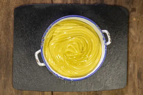 Una ciotola di cremosa crema pasticcera vegana, con un vortice lucido al centro, pronta per essere gustata.