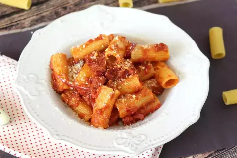 Piatto di rigatoni conditi con un sugo rosso piccante alla nduja, spolverati di parmigiano.