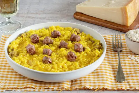 Un invitante risotto alla monzese, giallo intenso e arricchito da pezzetti di salsiccia, pronto per essere gustato.