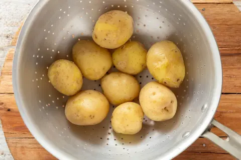 Patate bollite appena scolate in un colino, pronte per essere condite.