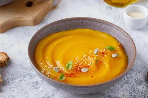 Vellutata di zucca cremosa, guarnita con semi di zucca, sesamo, paprika e basilico. Servita con crostini dorati.